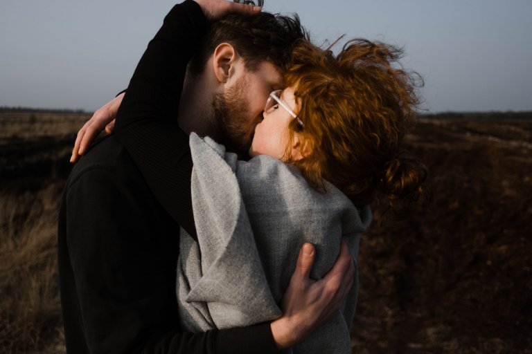 ein Mann und eine Frau küssen sich, sie legen die Arme umeinander