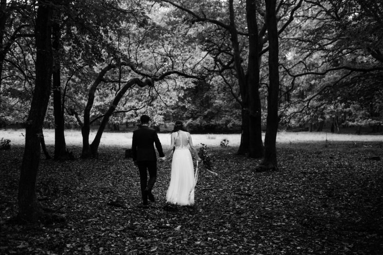 After-Wedding-Session-Hamburg- Brautpaar läuft durch den Wald in Richtung Lichtung