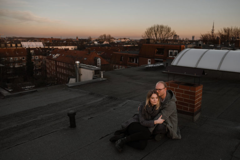 Paarogtografie Hamburg- Bilder im Sonnenuntergang über den Dächern Hamburgs. Sitzend ineinander gekuschelt auf dem Dach.