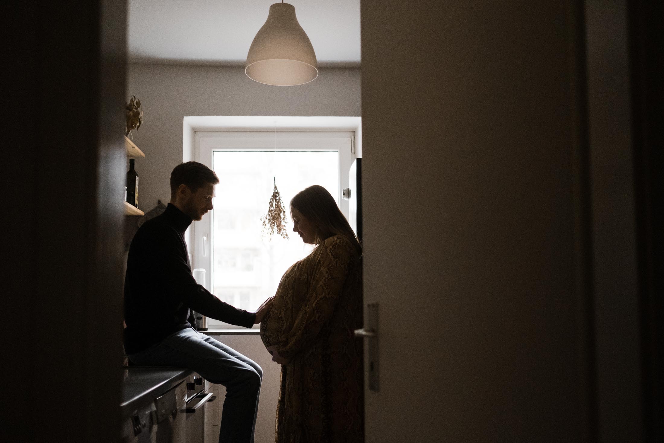 Familienfotografie Hamburg- Schwangerschaftsbilder- Paar blickt auf den Schwangerschaftsbauch