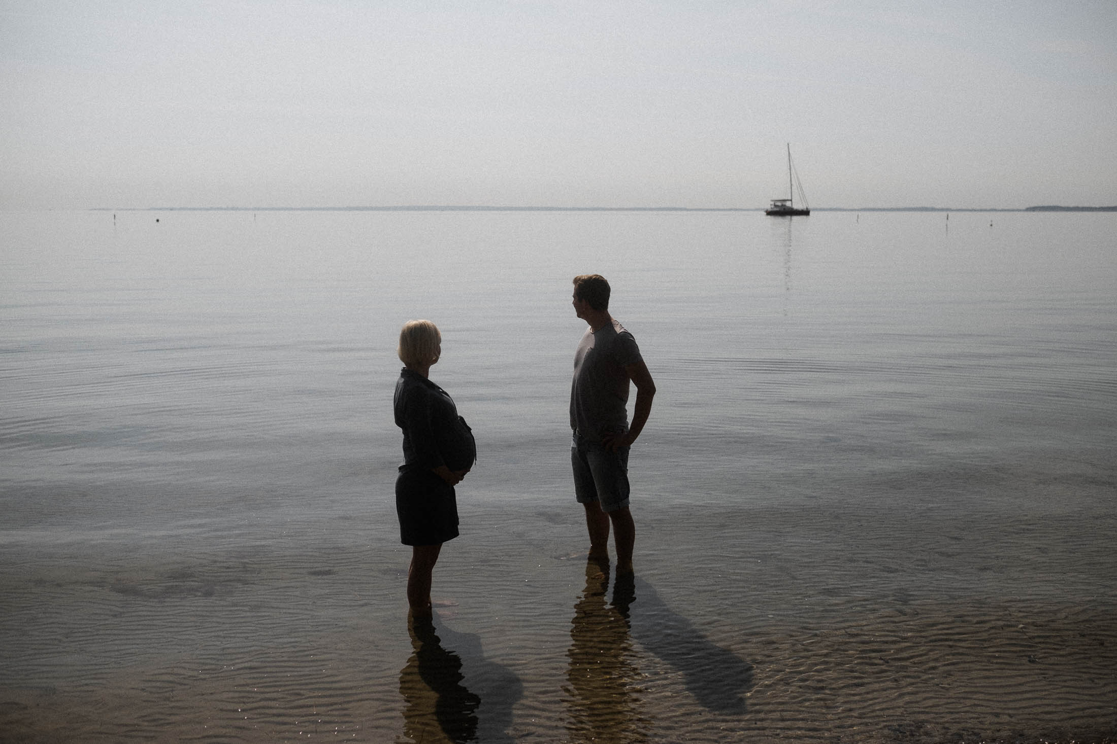 Familienfotografie Hamburg- Schwangerschaftsbilder Meer. Paar steht iim Wasser und schaut aufs Meer
