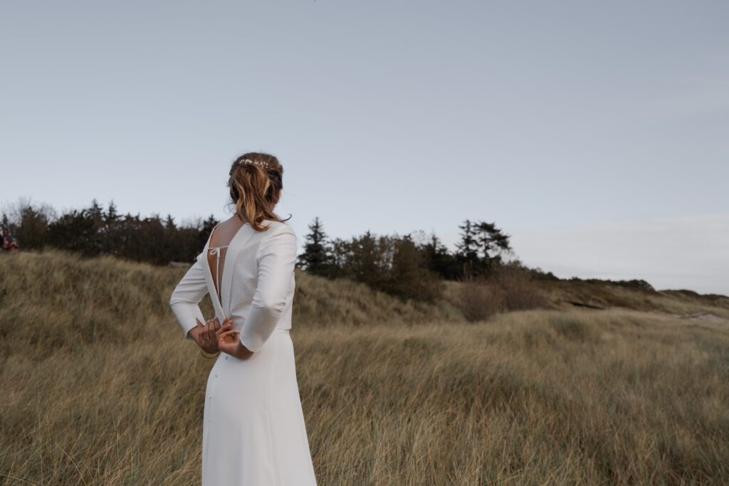 Hochzeitsfotograf Föhr- standesamtliche Trauung- Weingut Waalem- Hochzeitsportrait am Meer- Braut schaut auf die Dünen