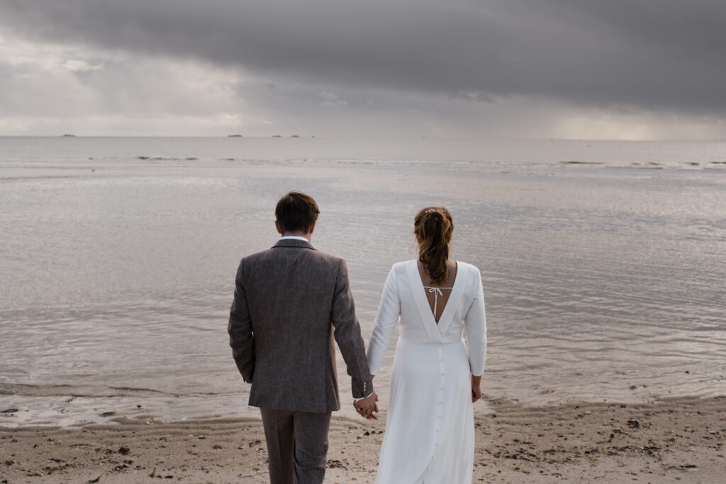 Hochzeitsfotograf Föhr- standesamtliche Trauung- Weingut Waalem- Hochzeitsportrait am Meer- Hochzeitspaar wandert auf das Meer zu