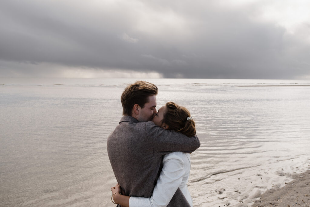 Hochzeitsfotograf Föhr- standesamtliche Trauung- Weingut Waalem- Hochzeitsportrait am Meer- Küssendes Hochzeitspaar am Meer