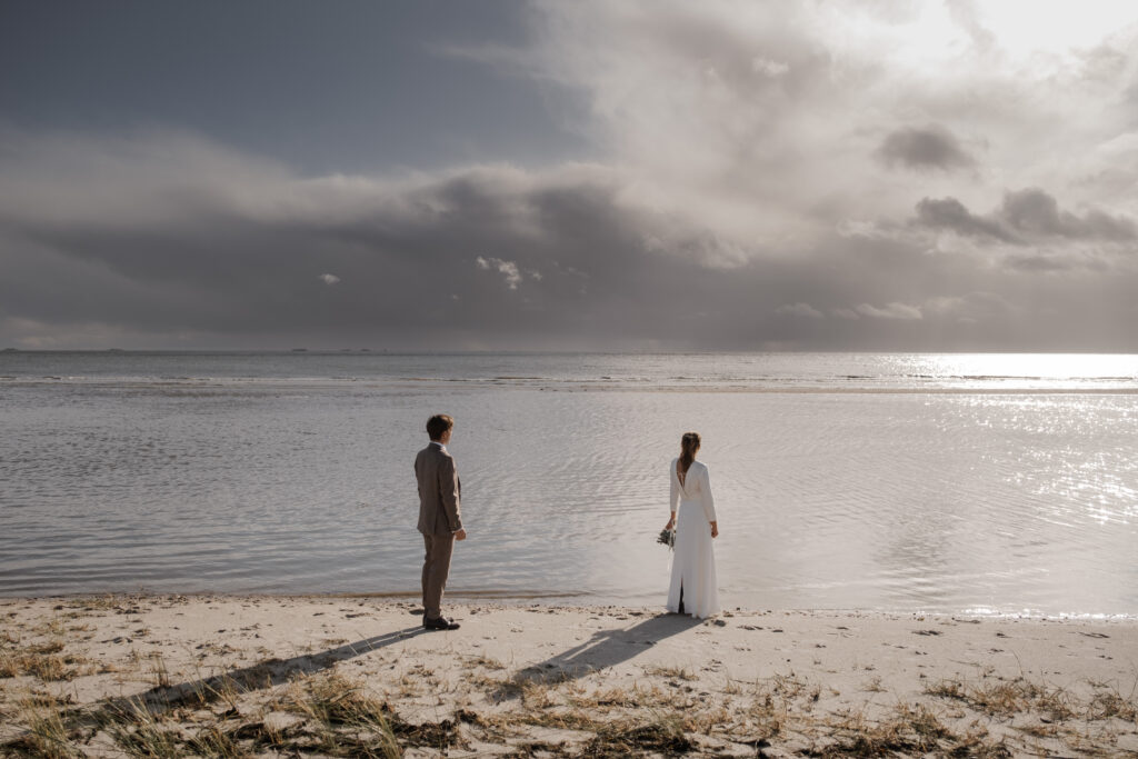 Hochzeitsfotograf Föhr- standesamtliche Trauung- Weingut Waalem- Hochzeitsportrait am Meer- Paar blickt aufs Meer