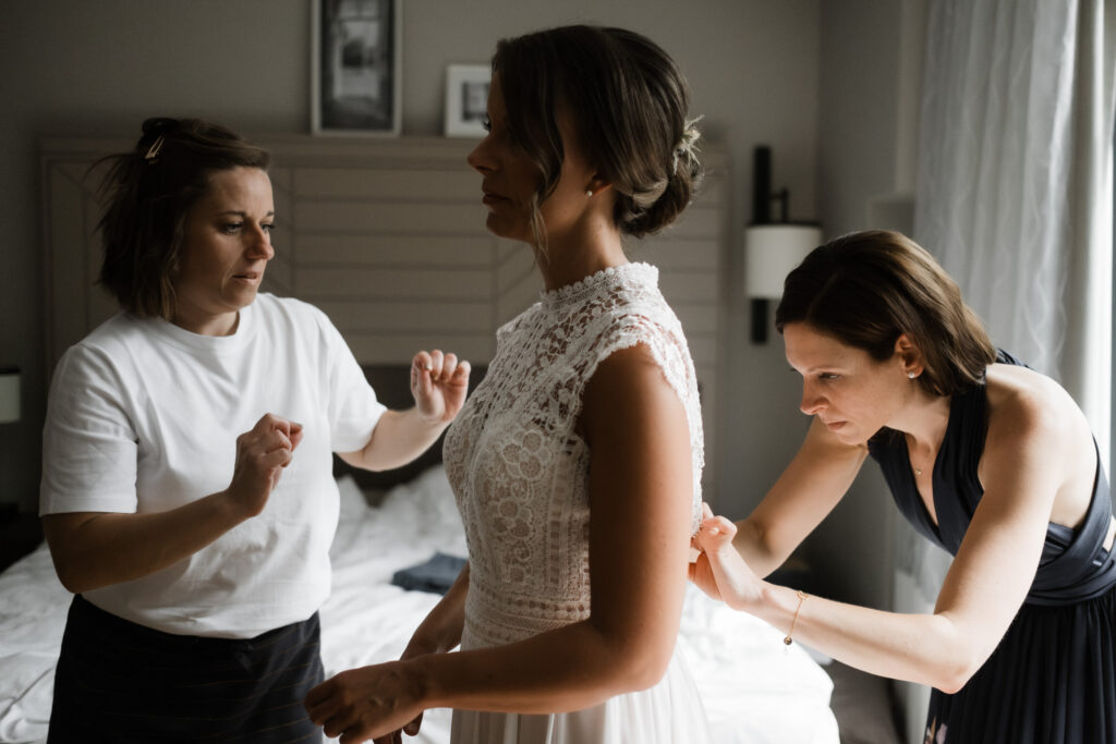 Hochzeitsfotografie Kieler Kaufmann-Getting Ready- Trauzeugin schließt das Hochzeitskleid