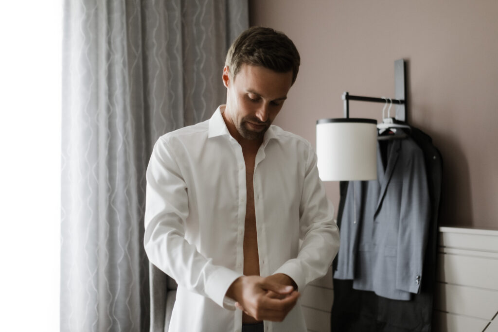 Hochzeitsfotografie Kieler Kaufmann-Getting Ready-Bräutgiam schließt das Hemd